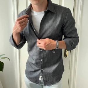 J.lindberg overshirt tröja  - Grå skön j.lindberg overshirt, inga större defekter förutom att något lite konstigt i materialet har ändrats på ena ärmen. Kolla slide 5, märks inte när man använder dock! Modellen är 180,75 kg och bär M slim fit. 