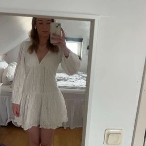Student klänning - Superfin vit  klänning med broderade detaljer och v-ringning. Klänningen har långa ärmar, lätt volang i kjolen och ett luftigt, romantiskt tyg. Perfekt för sommarens alla tillfällen och ger en fräsch och söt look.