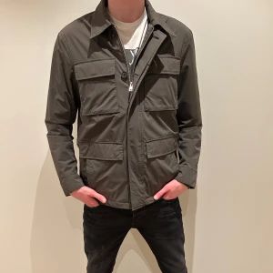 Grön jacka från Massimo Dutti - Snygg grön jacka från Massimo Dutti med flera praktiska fickor och dragkedja. Perfekt för en stilren look. Jackan har långa ärmar och en klassisk krage. Inköpt i februari detta året! Helt ny!