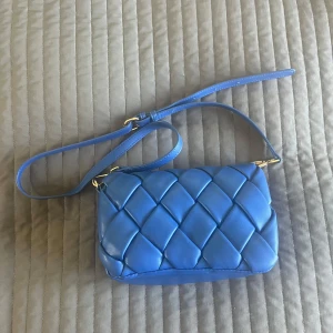 Blå quiltad axelväska från Noella - Bara använd en gång och är i mycket fint skick.  Snygg blå axelväska från Noella med quiltad design och justerbar axelrem. Skriv vid frågor och funderingar 🤗