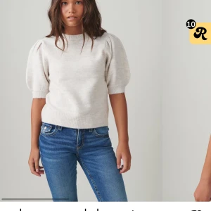 Beige stickad tröja med puffärm - Superfin beige stickad tröja med korta puffärmar och rund hals. Tröjan har ribbade muddar vid ärmslut och nederkant, vilket ger en snygg och modern look. Perfekt att styla med jeans eller kjol för en trendig outfit.