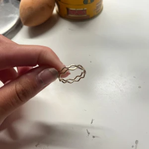 Guldig vågig ring i metall - Säljer 2 snygga guldig ringar en med löv på som är justerbar och andra med vågit mönster! Båda köpte på second hand 