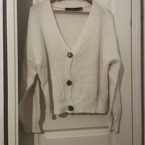 Vit stickad kofta - Mysig vit stickad kofta från Vero Moda med djup v-ringning. 