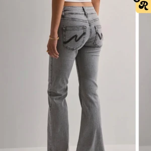 Grå bootcut jeans med broderade fickor - Gråa jeans från Nelly med broderade fickor strl 38, köpta för 699kr och använda ca 2 gånger. Säljer då de är lite små för mig💕innerbenslängden är 84-85 cm❤️ 