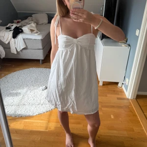 Vit kort sommarklänning med knyt - Supersöt vit kort klänning med tunna axelband som knyts på axlarna och söt rynkdetalj vid bysten. Klänningen har dragkedja i sidan och är gjord i ett lätt, luftigt tyg som passar perfekt för varma dagar. ifrån shein