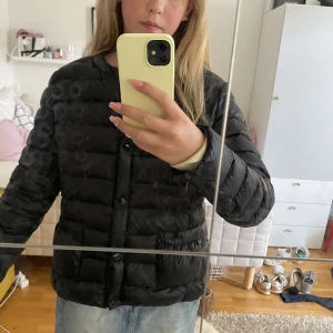 Svart dunjacka Holly & Whyte Lindex - Säljer en svart dunjacka från Holly & Whyte by Lindex i storlek L men känns som en S/M. Jackan är quiltad med knäppning framtill och har två fickor. Perfekt för kyliga dagar och har en clean, enkel look som funkar till det mesta.