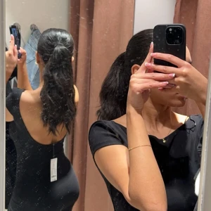 Svart långklänning med öppen rygg - Använd en gång, sömmen har gått upp lite men ingenting som skapar ett hål (se bilder) - enkelt att sy ihop. Svart långklänning med tight passform och öppen rygg. Klänningen har korta ärmar och är sydd i ett stretchigt material.