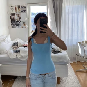 Ljusblå ribbad linnetopp - Supersöt ljusblå ribbad linnetopp med breda axelband och fyrkantig halsringning. Toppen är figurnära och har en fräsch, somrig vibe. Perfekt att styla med jeans eller kjol för en chill look.