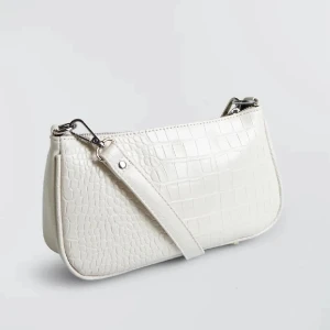 Vit axelväska i skinn - Snygg vit axelväska med krokopräglat mönster och avtagbar axelrem. Väskan har en stilren, avlång form och silvriga metalldetaljer. Perfekt för dig som vill ha en trendig och clean accessoar till din outfit.
