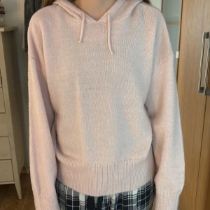 Ljusrosa stickad hoodie från Gina Tricot Young - Supermjuk ljusrosa stickad hoodie från Gina Tricot Young i storlek 170 med huva och dragsko. Tröjan har ribbade muddar och avslut, samt lång ärm. Perfekt för dig som gillar en chill och söt stil. Använd ett fåtal gånger.