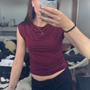 Vinröd ärmlös topp från 157 XS - Säljer en vinröd ärmlös topp från 157 i storlek XS. Toppen är croppad och har en enkel, clean design med rund halsringning. Perfekt att matcha med höga jeans eller kjol för en chill look.