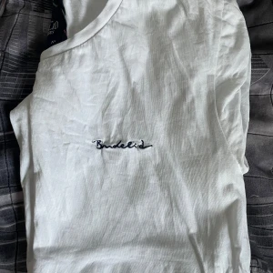 Vit t-shirt från Bondelid - Vit t-shirt från Bondelid med broderad logga på bröstet. Klassisk och stilren design i mjuk bomull, perfekt för en clean och enkel look. Rund halsringning och normal passform gör den lätt att matcha med allt.