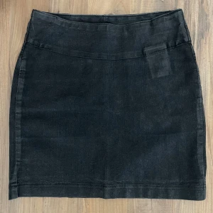 Svart jeanskjol från Lee - Svart kort jeanskjol från Lee med klassisk femficksdesign och raka linjer. Kjolen har två bakfickor med Lee-logga och är tillverkad i ett slitstarkt denimtyg. 