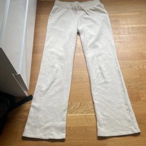 Beiga mjukisbyxor från H&M med snörning - Säljer ett par beiga mjukisbyxor från H&M i storlek 164. Byxorna har en bred ribbad midja med snörning och raka ben. Perfekta för chill dagar eller när du vill vara extra bekväm. Mjukt material och enkel stil som passar till allt.