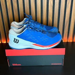Wilson Rush Pro Ace Clay blå tennisskor - Säljer dessa Wilson Rush PRO Ace Clay i storlek 42 2/3. Har spelat i de 2 timmar men de kändes lite för små för mig, därav säljer jag. Köpta för 1200kr från Racketshopen.   Kan fraktas emot fraktkostnad eller hämtas upp i Bjärred!   Har du några frågor, skriv gärna!