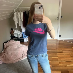Blå Nike t-shirt med rosa logo - Snygg blå t-shirt från Nike med stor rosa logga framtill. Rund halsringning och korta ärmar. Barnstorlek M, 137-146cm men tycker den sitter som XS vanlig storlek. 💕