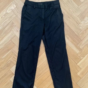 Svarta kostymbyxor Massimo Dutti - Raka kostymbyxor med tunna fina ränder från Massimo dutti. De är låga i midjan med fina detaljer bak på fickorna samt runt midjan. Jag har sprättat upp benen längst ned så att de skulle passa mig i längden, jag är 161 och de är bra i längden på mig men skulle även passa på någon som är några cm kortare eller längre! Storlek 36/26.