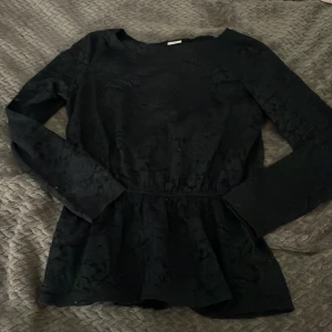 Svart spetsblus från Jacqueline de Yong - Supersnygg svart blus i spets från Jacqueline de Yong. Blusen har lång ärm, markerad midja och ett vackert blommigt spetsmönster som ger en cool och elegant vibe. Perfekt för dig som vill sticka ut lite extra med detaljerad design. Jätte snygg men kommer tyvärr inte till användning❤️