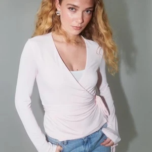  omlottopp - Supersöt ljusrosa omlottopp med långa ärmar och knyt i sidan. Tunn och mjuk i materialet, perfekt för lager-på-lager. Nypris 330 jr, denna är i nyskick