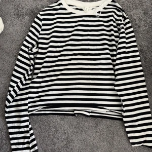Randig långärmad tröja från H&M - Säljer en svartvit randig långärmad tröja från H&M i storlek XL. Tröjan har klassiska horisontella ränder och rund halsringning med vit kant. Perfekt för en chill och stilren look. Materialet är mjukt och skönt, troligtvis bomull.