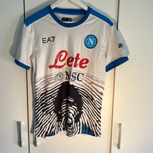Fotbollströja Napoli ÖPPEN TILL BUD - Säljer en special edition MARADONA fotbollströja från EA7. Tröjan är väldigt cool och riktigt snygg och väldigt ovanlig. Den har varit använd ett par gånger som du ser på etiketten men är fortfarande i toppskick! Tveka inte att skriva och fråga vid minsta fundering!🤗 Öppen till bud!🤗😊🙌