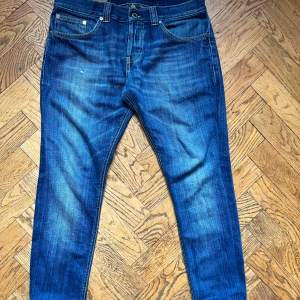 Blå jeans från Dondup -  W30 men väldigt korta! Snygga blå jeans från Dondup med klassisk femficksdesign och coola slitningar. Jeansen har normal passform, raka ben och detaljerade sömmar. Tillverkade i mjukt denimtyg som känns skönt hela dagen. Perfekta för dig som gillar en avslappnad men stilren look.