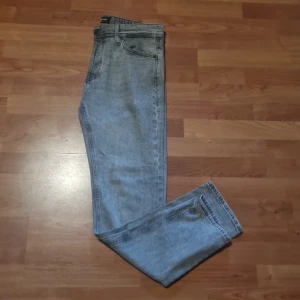 Grå tapered jeans Jack & Jones 30/34 - Snygga grå jeans från Jack & Jones i modellen Tapered/Mike. Jeansen har en avsmalnande passform och klassisk femficksdesign. Tillverkade i mjukt denimtyg som ger en avslappnad men stilren look. Perfekta för dig som gillar en modern siluett.