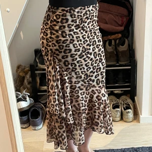 Leopardmönstrad volangkjol - Säljer en snygg långkjol med leopardmönster och volangdetaljer. Kjolen har omlottkänsla och är i ett lätt, flowy material.