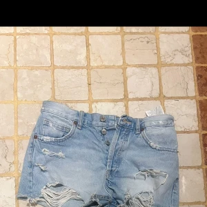 Ljusblåa ripped jeansshorts - Snygga ljusblå jeansshorts med låg midja och slitna detaljer från Zara!. Shortsen har klassisk femficksdesign, knappar framtill och råa kanter nertill. Perfekta för en chill sommarlook.