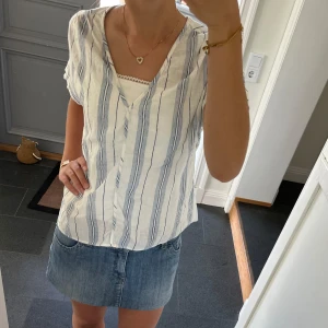 Vit randig topp  - Blå/vit kortärmad blus från H&M i storlek S. Fint skick. Säljer även kjolen. Använd gärna köp nu!