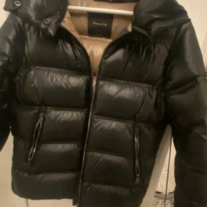 Svart pufferjacka från Massimo Dutti - Säljer en svart pufferjacka från Massimo Dutti med beige luva som går att ta av! Jackar har använts ungefär 2 vintrar i rad då det finns små defekter på den! Fråga om mer bilder på defekterna privat eftersom jag inte fick in dom här. ❤️Nypris 200kr