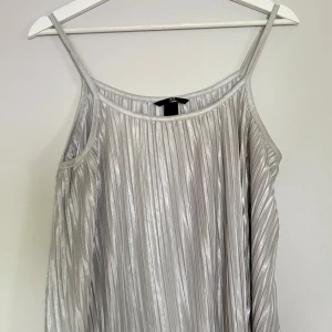Plisserad silverlinne från H&M - Snygg plisserad linne i metallic silver från H&M.