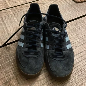 Adidas Spezial sneakers i mörkblå mocka - Säljer ett par Adidas Spezial sneakers i mörkblå mocka med ljusblå ränder och detaljer. Skorna har klassisk gummisula, snörning och rund tå. Perfekta för dig som gillar retrostil och streetwear. Ikonisk guldfärgad Spezial-logga på sidan.