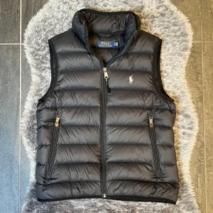 Polo Ralph Lauren Väst Svart - Svart väst från Ralph Lauren i storlek S. Klassisk modell med diskret logga – passar perfekt som lagerplagg över hoodie eller skjorta. I mycket fint skick, sparsamt använd.