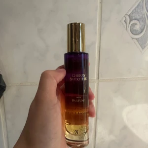Zara Cherry Smoothie parfym - Cherry Smoothie Eau de Parfum från Zara med en snygg flaska i lila och guldtoner. Flaskan har en elegant guldig kork och genomskinlig glasdesign som skiftar från lila till bärnstensfärgat. Perfekt för dig som gillar fruktiga dofter.