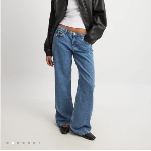 Blå wide jeans från NA-KD låg midja - Säljer ett par blå jeans från NA-KD med låg midja och  breda ben. Klassisk femficksmodell i jeansmaterial. Endast testade så prislapp är kvar. Nypris: 699kr storlek 38 💙