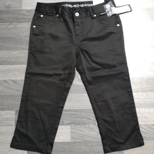 Nya Svarta straight 3/4 dels byxor, piratbyxor, trekvarts från Vila - Svarta byxor från Vila i straight fit med regular midja och raka ben. Byxorna har klassiska fickor fram och bak, samt snygga dragkedjor på bakfickorna. Materialet är mjukt och känns bekvämt, perfekt för en clean och stilren look.