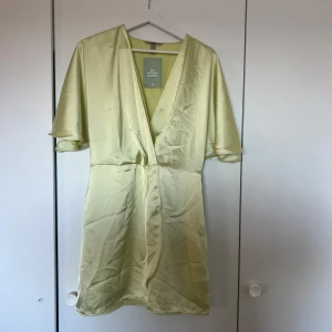 Ljusgul klänning  - Snygg ljusgul klänning från hm i satin. Klänningen har korta ärmar och en v-ringad design som ger en elegant touch. Perfekt för sommarens alla tillfällen den har även en dragkedja på sidan🫧💕
