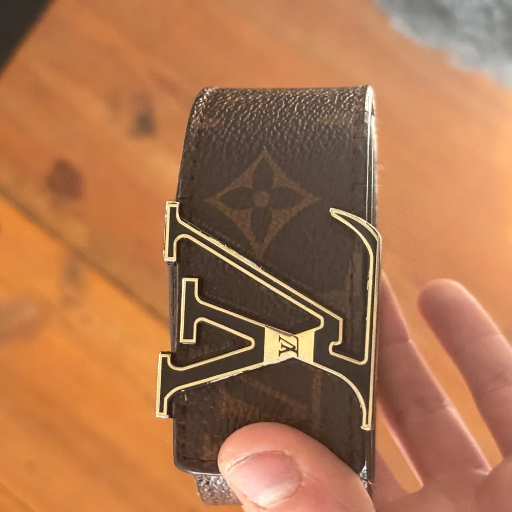 Snyggt brunt bälte från L V med det klassiska monogrammönstret och en stilren L Vspänne i guld. Perfekt för att ge en lyxig touch till din outfit.. Muu.