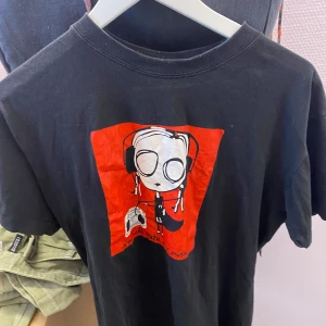 Svart t-shirt med tryck - Cool svart t-shirt med ett unikt tryck av en figur med hörlurar och texten 'You will hate my music'. Perfekt för dig som gillar att sticka ut med din stil. T-shirten har korta ärmar och en normal passform.