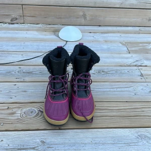 Vinröda vinterkängor med snörning - Säljer ett par vinröda vinterkängor med svart foder och snörning. De har en robust sula och är perfekta för kalla dagar. Kängorna har en snygg kombination av vinrött och svart, vilket ger dem en stilren look.