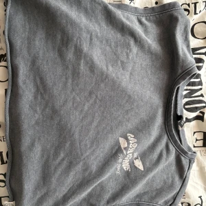 Grå tröja från Divided - Säljer en grå tröja från Divided med ett coolt tryck av en sköldpadda och palmer på baksidan. Tröjan har rund hals och ribbade kanter. Perfekt för en avslappnad stil. 🌴🐢