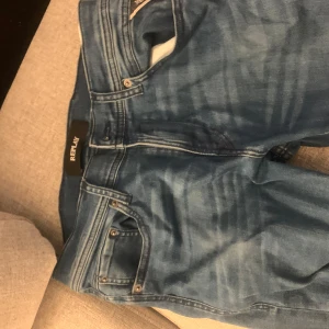 Blå jeans från Replay - Snygga blå jeans från Replay med klassisk femficksdesign och dragkedja. De har en stilren look med Replay-logga på baksidan och är perfekta för en avslappnad stil.