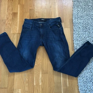 Mörkblå jeans från Replay - Snygga mörkblå jeans från Replay, modell Anbass. De har en klassisk femficksdesign och en diskret logga på bakfickan. Perfekta för en stilren look. Priset är inte hugget i sten så här av er vid intresse storlek: 30 32