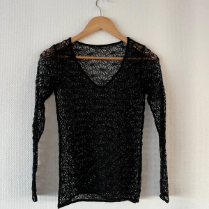 Svart spetsblus - Säljer en trendig svart spetstopp med v-ringning som man kan ha framtill eller i ryggen långärmad design. spetsen är blomstermönstrad🖤🌸