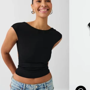 Svart ärmlös topp med öppen rygg - Snygg svart ärmlös topp med en stilren design och öppen rygg. Perfekt för en trendig look. Tillverkad i ett mjukt material som känns skönt mot huden. Tröjan är oanvänd