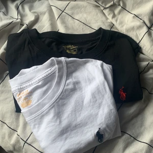 Svart och vit t-shirt från Polo Ralph Lauren - Två klassiska t-shirts från Polo Ralph Lauren i svart och vitt. Båda har den ikoniska broderade loggan på bröstet. Perfekta för en stilren och avslappnad look.