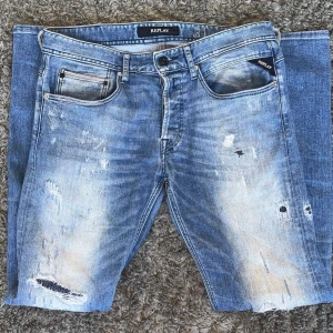 Replay jeans med slitningar - Snygga blå jeans från Replay med slitna detaljer. Inga av slitningarna går igenom, Skinnyfit i storlek W31/L32. Skriv vid funderingar!