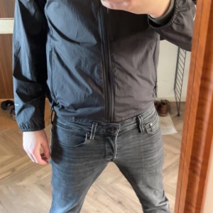 Svart vindjacka från The North Face - Säljer en svart vindjacka från The North Face med huva och dragkedja. Jackan har långa ärmar och logotypen tryckt på bröstet och ärmen. Perfekt för blåsiga dagar. Den är storlek barn xl så runt 170 men den passar nästan mig som är 183 den är lite liten då bara!