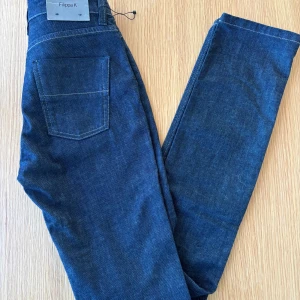 Mörkblå jeans från Filippa K - Snygga mörkblå jeans från Filippa K i en klassisk design. De har en rak passform med fem fickor och knappgylf. Perfekta för en stilren look.